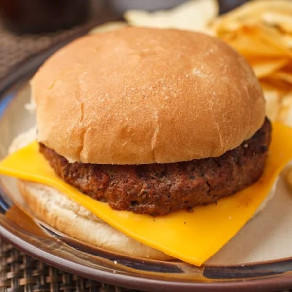 A Steak-Out cheeseburger with a thick patty and melted cheese, served with potato chips.