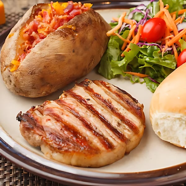 Grilled steak, loaded baked potato, side salad, and a dinner roll on a plate.